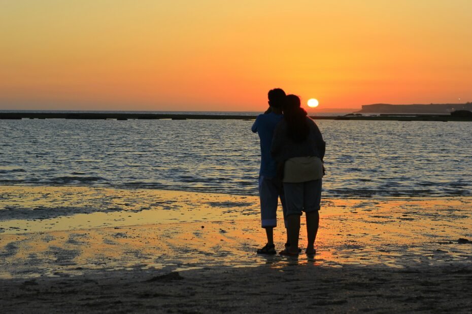couple standing on beach during sunset